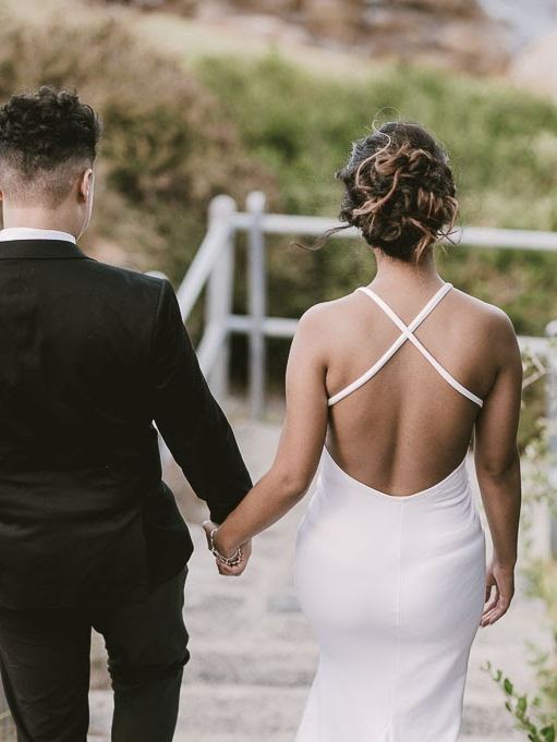 Bride walking away holding hands with her groom, textured updo with loose curls
