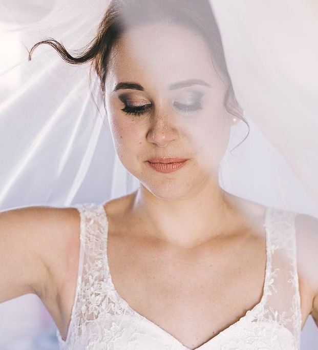 Bride with dramatic lashes and a smoky bronze eye look under a veil